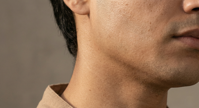 Close-up of a man's neck and part of his face against a neutral background