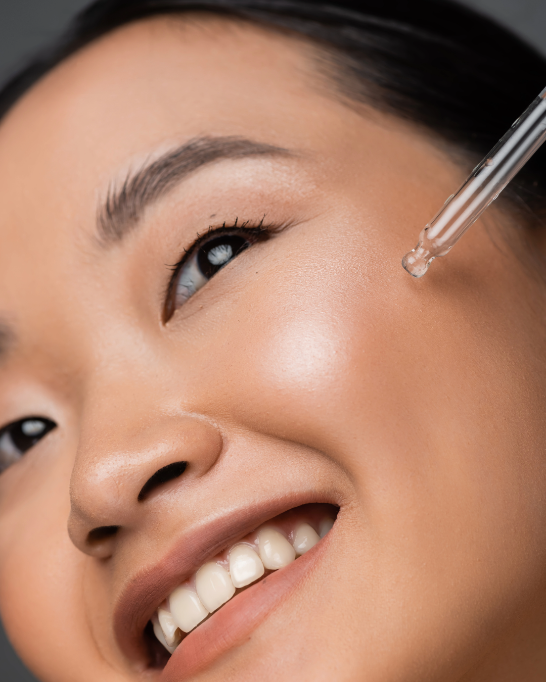 An Asian model applying MEANT 5% Niacinamide De-Tan Glow Face Serum with Hyaluronic Acid & Natural Aloe Vera with its transparent dropper on her face. 